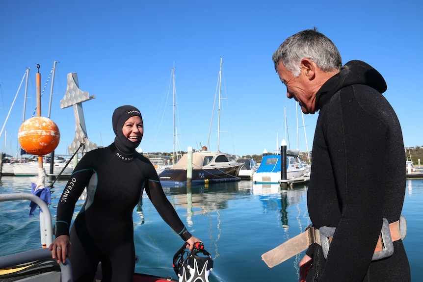Researchers Pang Quong and Sheree Marris in wetsuits on their small boat in Port Phillip Bay.