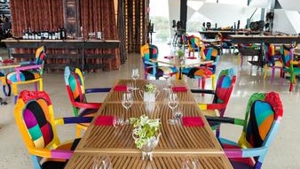 colourful chairs around a table with wine glasses on it, in a restaurant
