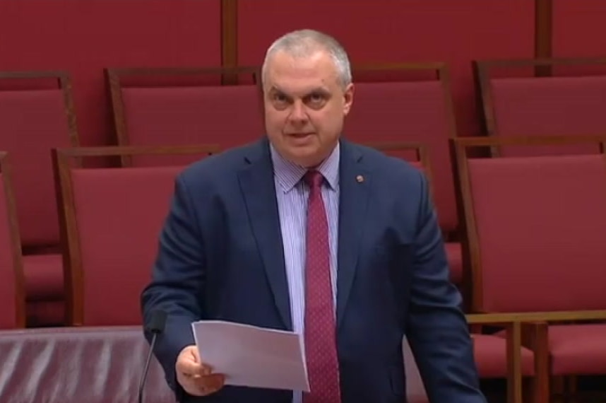 A man in a suit in front of red seats