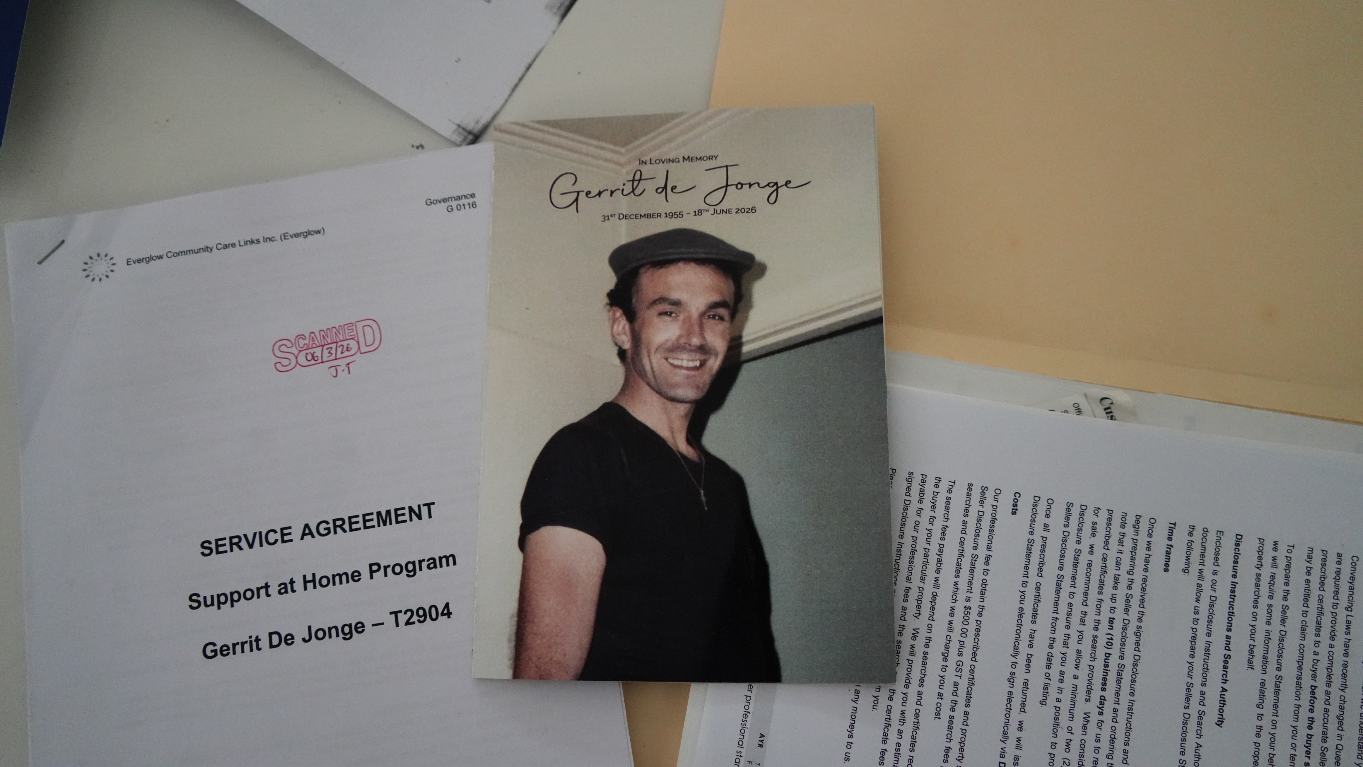 cardboard paper with photo of man with black shirt and small hat on table with documents