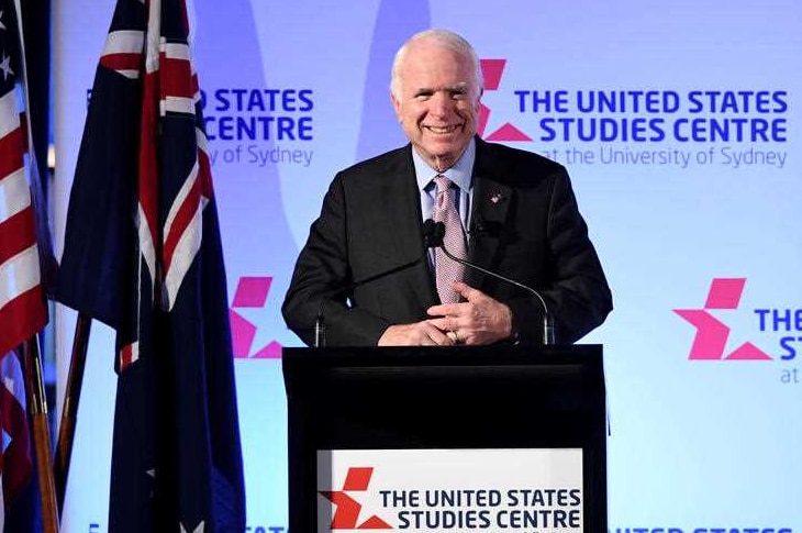 John McCaine at a podium with the US and Australian flags and a backdrop saying 'The United States Studies Centre' behind him