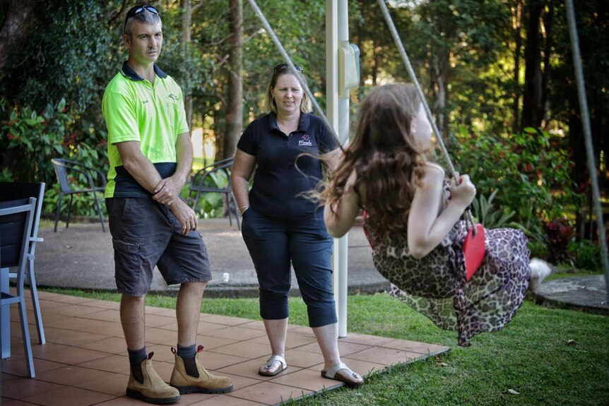 Scott and Kristy Aitken watch one of their two daughters play on a swing.