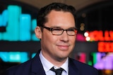 Bryan Singer smiles in a suit at a movie premiere
