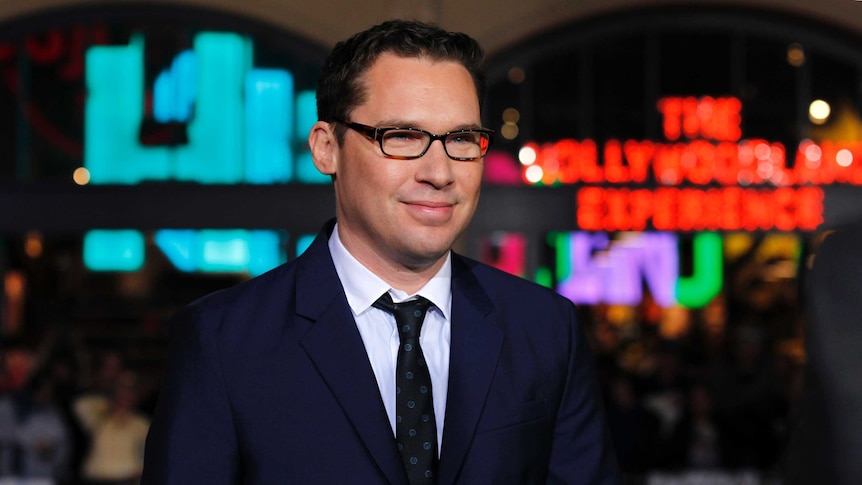 Bryan Singer smiles in a suit at a movie premiere