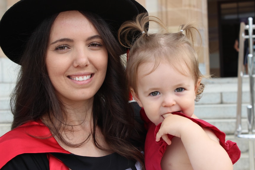 A young woman with a graduation hat and her child.