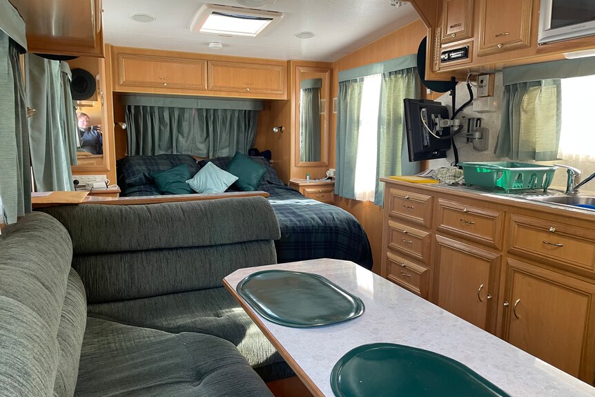 Interior living area of modern van with comfy couch and bed.