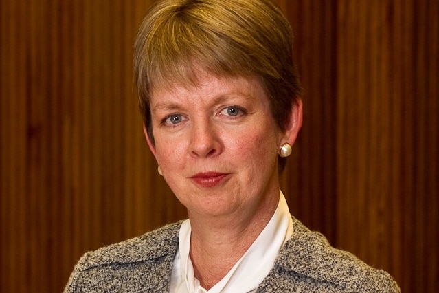 A profile photo of a woman in front of a brown background