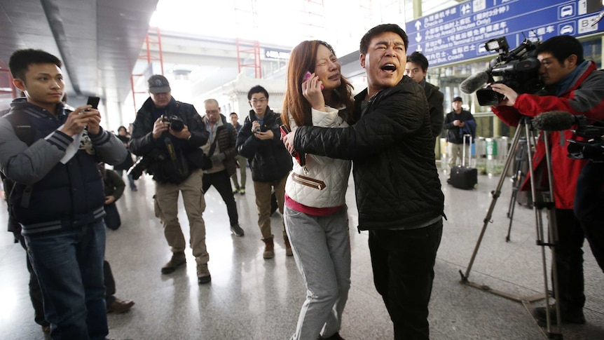 A woman cries as she talks on her mobile phone at Beijing Capital International Airport