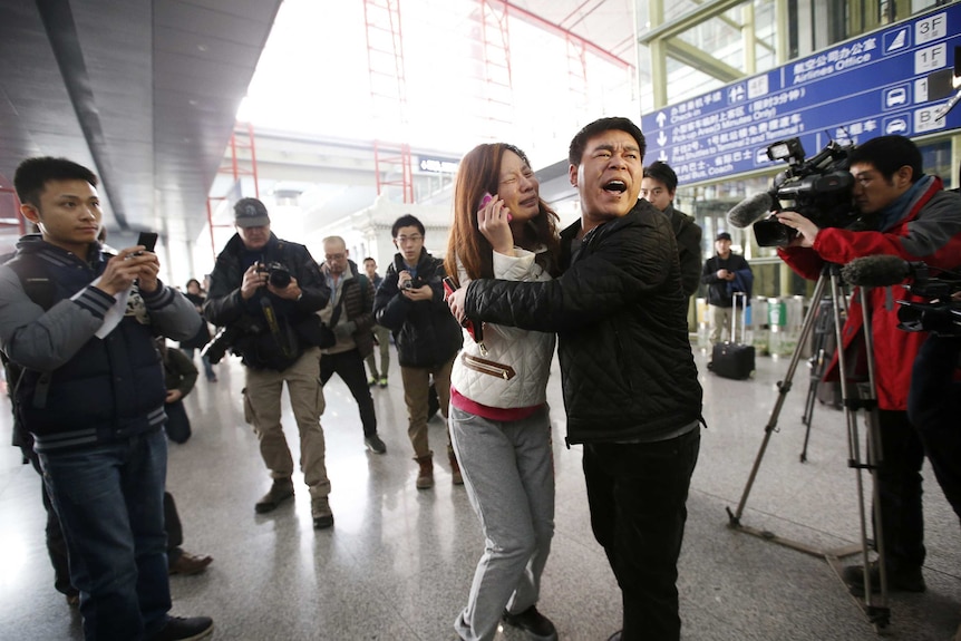 A woman cries as she talks on her mobile phone at Beijing Capital International Airport