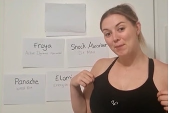 Netballer Eleanor Cardwell is wearing a black sports bra and standing in front of a white wall with pieces of paper.
