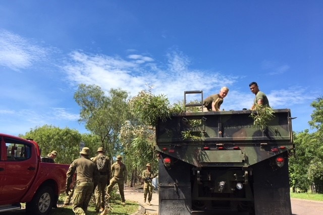 US Marines throw broken trees into a defence vehicle.