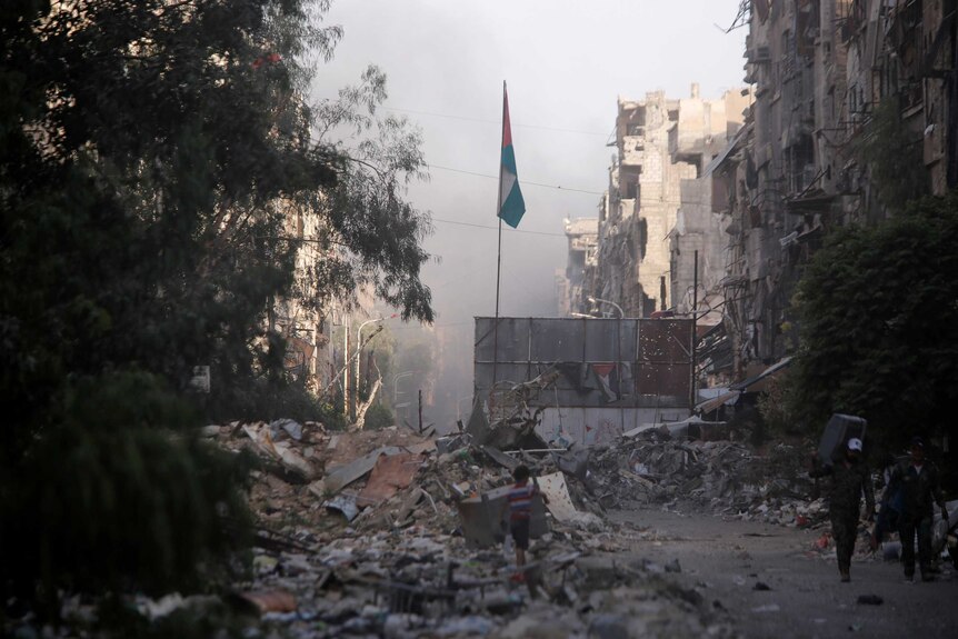 A boy stands on the rubble of damage buildings in Yarmouk Palestinian camp.