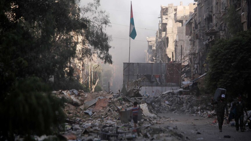 A boy stands on the rubble of damage buildings in Yarmouk Palestinian camp.