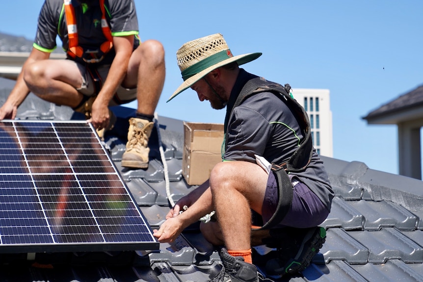 Electricians place solar panels on roof