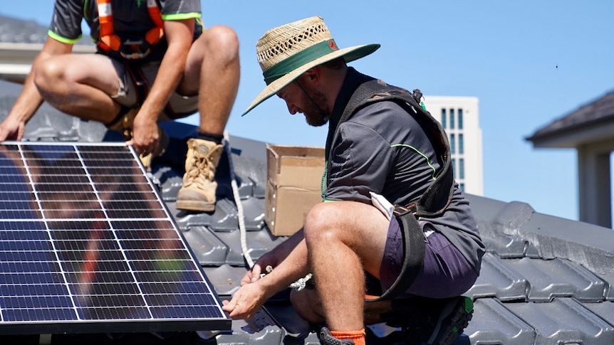 Electricians place solar panels on roof