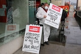 Kevin Harkins holds asbestos sign outside Royal Hobart Hospital