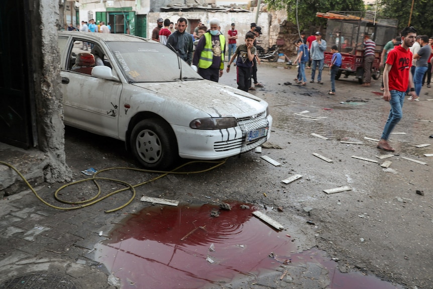A damaged car sits behind a pool of blood and other debris