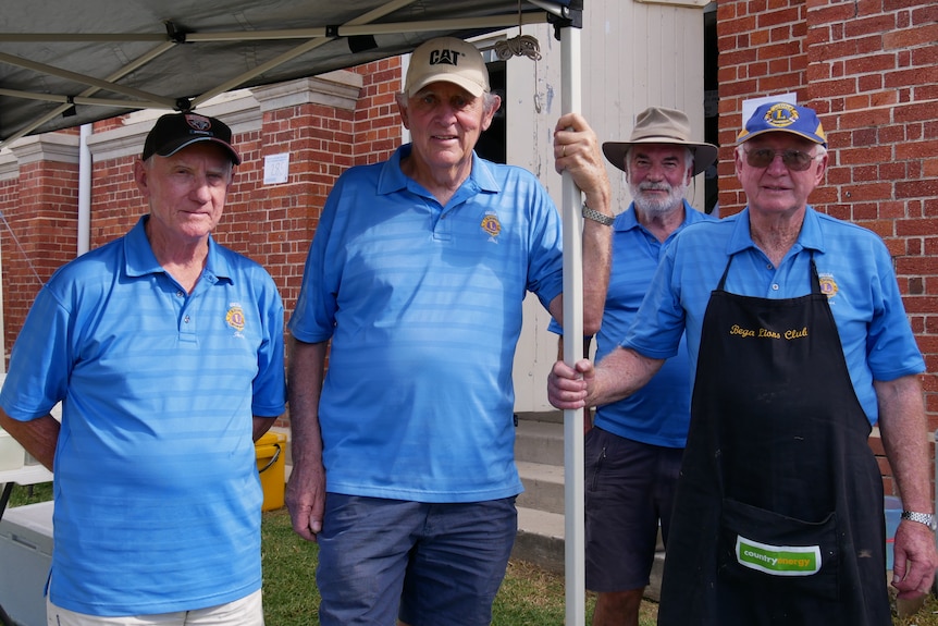 Four men aged in their 70s and 80s near a BBQ.