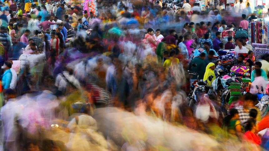 A crowded market, the center path of people blurred as they move. 