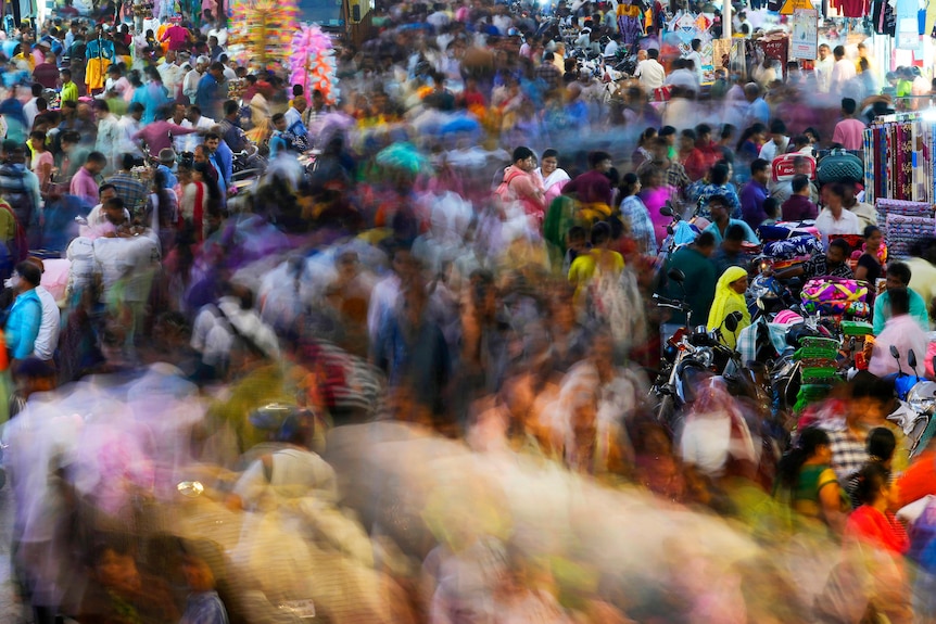 A crowded market, the center path of people blurred as they move. 