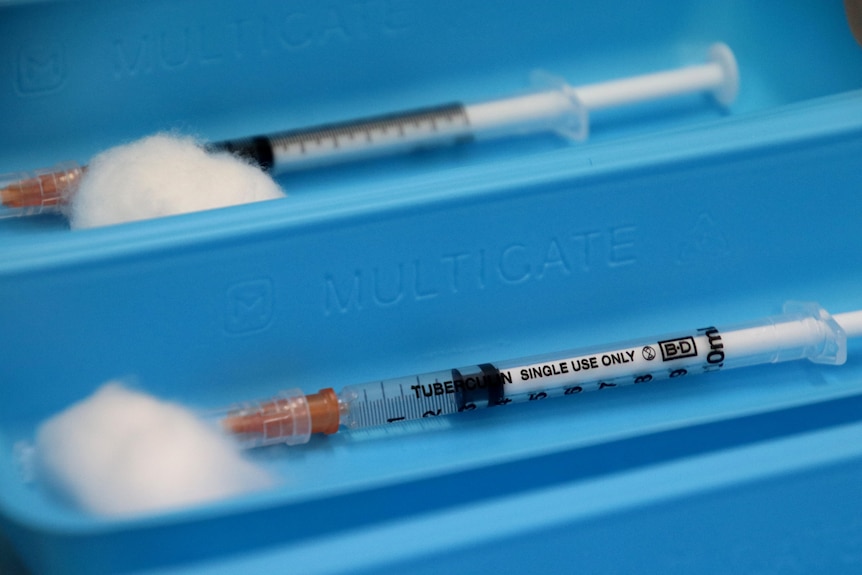 Tow needles and syringes in a blue tray.