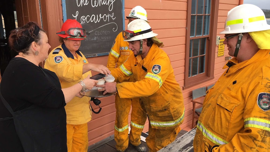 A woman serves firefighters coffees