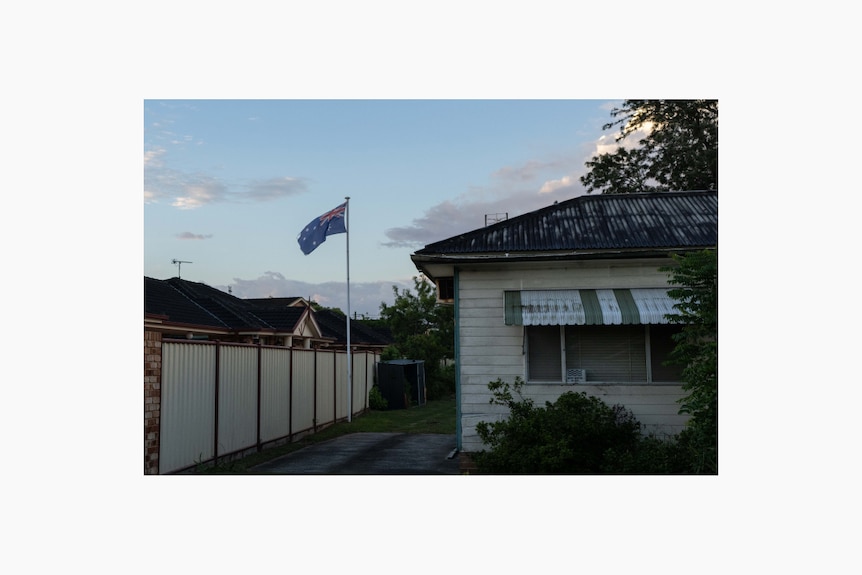 A house, just after sunset, with an Australian flag blowing in the wind.