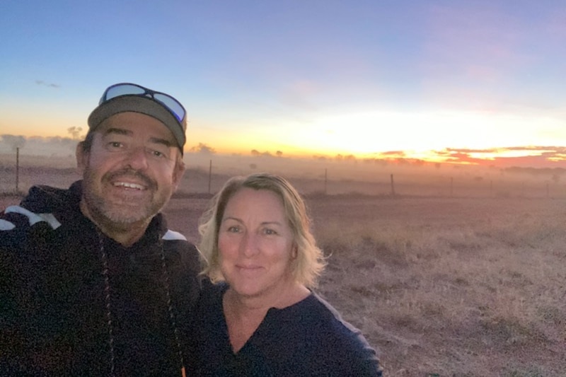 Kerry Turley and his wife stand outside, with the sunset behind them.