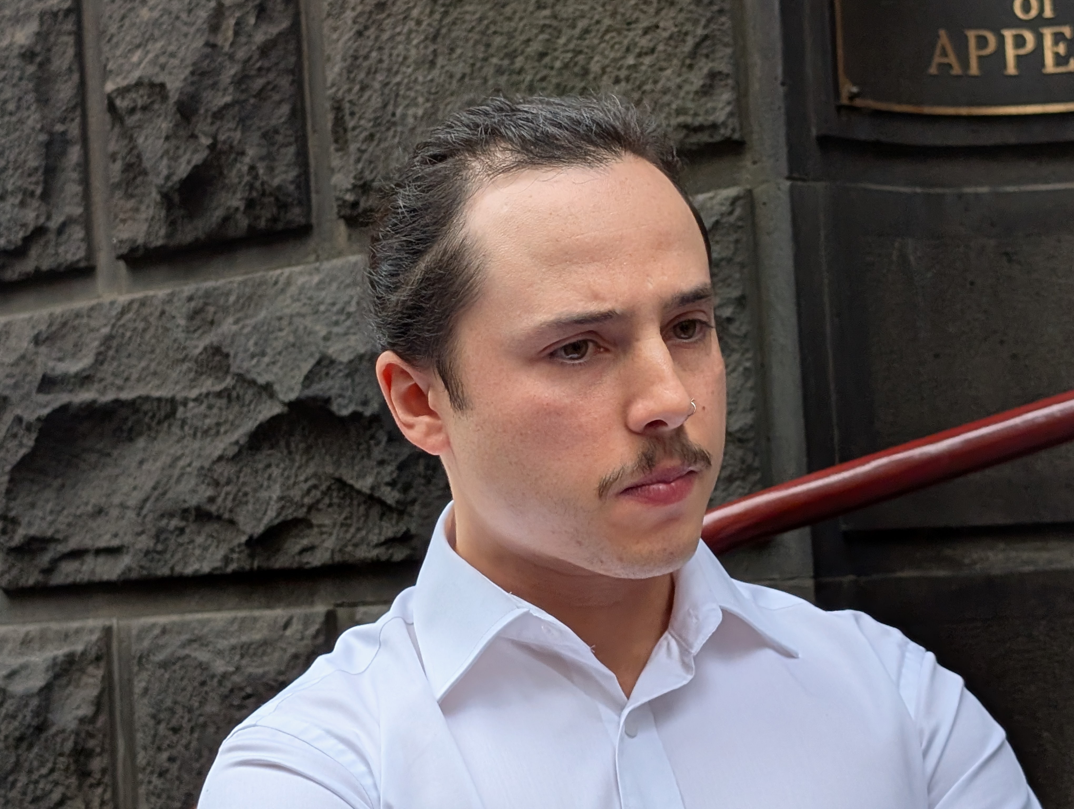 A man in white with dark hair and a ponytail
