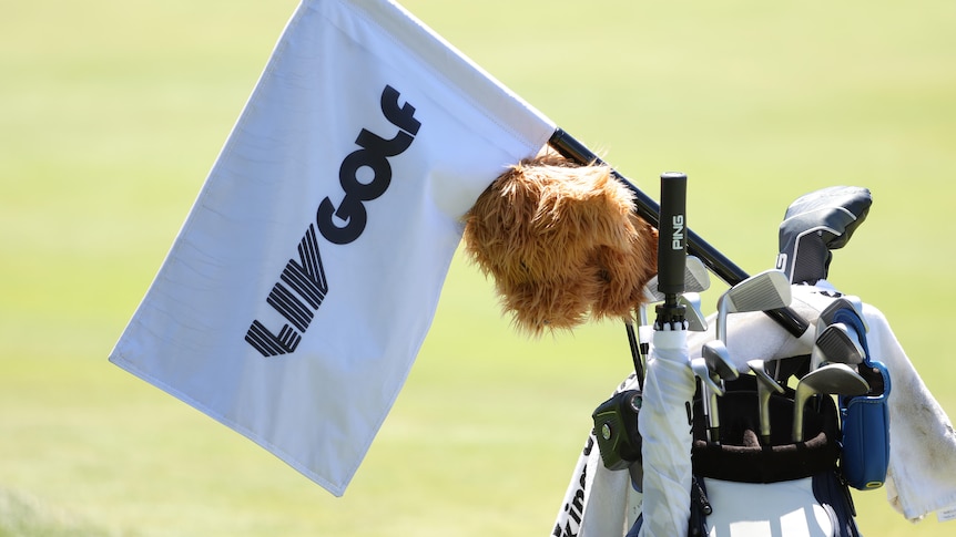 A flag featuring the words "LIV Golf" on it rests on top of a golf bag. 