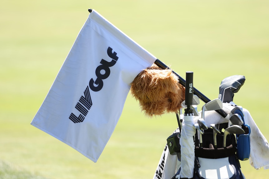 A flag featuring the words "LIV Golf" on it rests on top of a golf bag. 