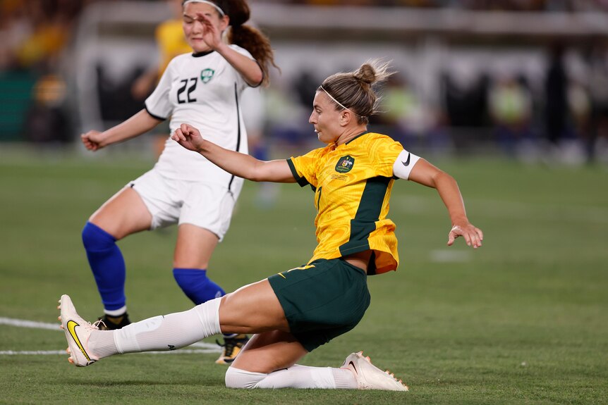  Steph Catley with her leg extended kicking a goal. 