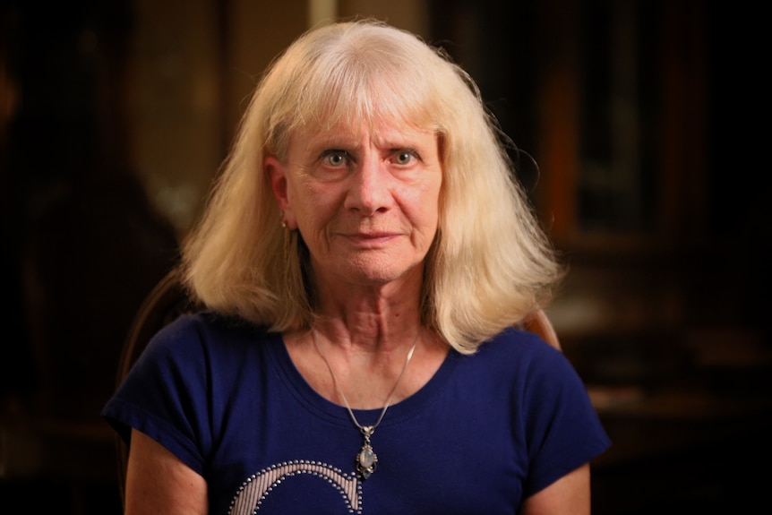 A woman wearing a necklace and blue top.