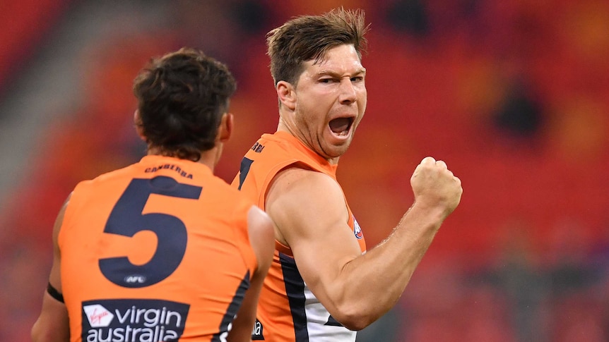 A GWS Giants players pumps his right first as he looks to his right while celebrating a goal against Richmond.