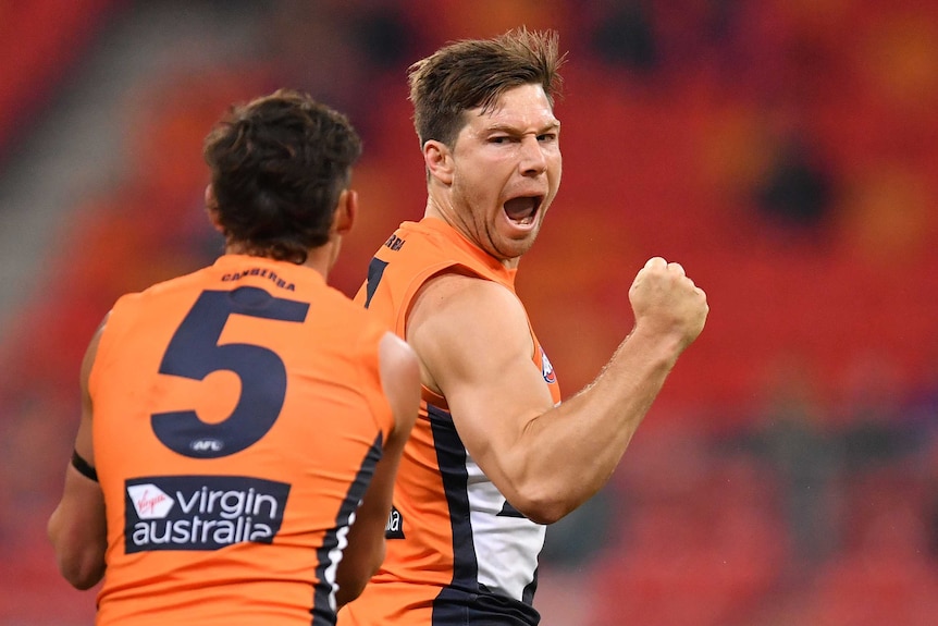 A GWS Giants players pumps his right first as he looks to his right while celebrating a goal against Richmond.