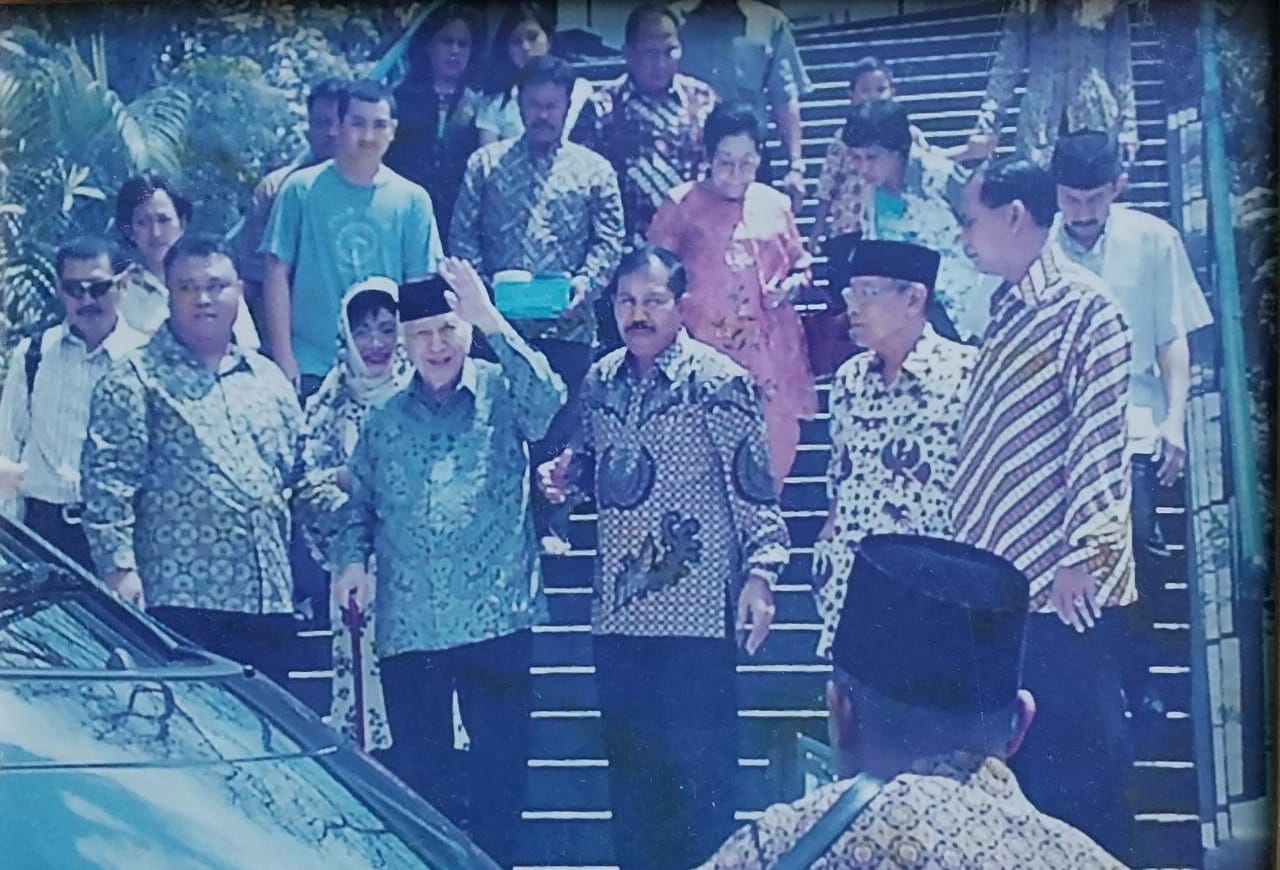 Indonesian former president Suharto going down the stairs followed by people.