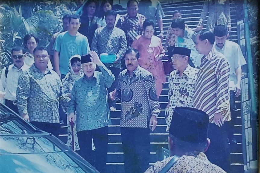 Indonesian former president Suharto going down the stairs followed by people.