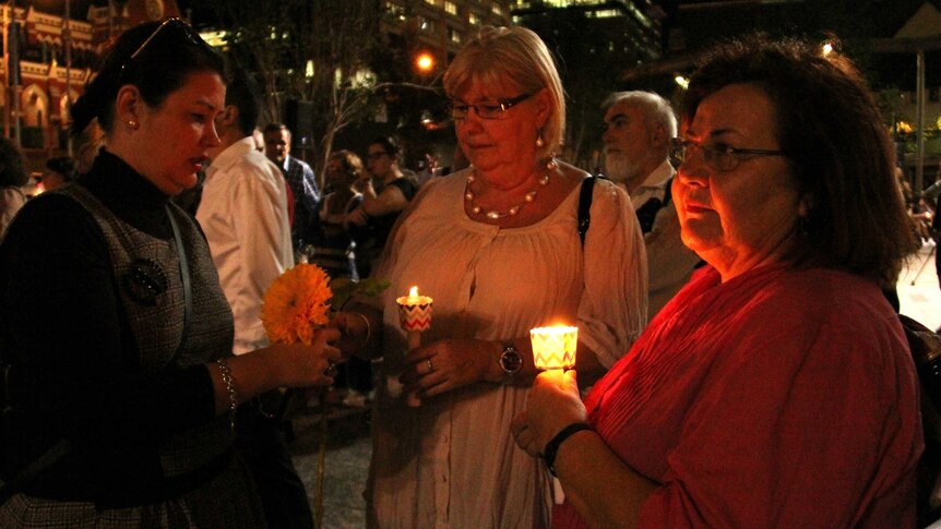 Women hold candles and flowers at the Sophie Collombet march