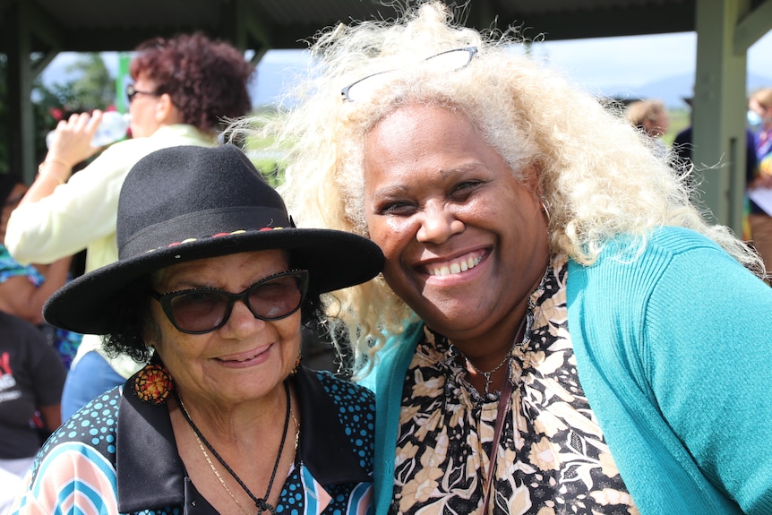 An indigenous woman and south sea islander woman stand together smiling at the camera. 