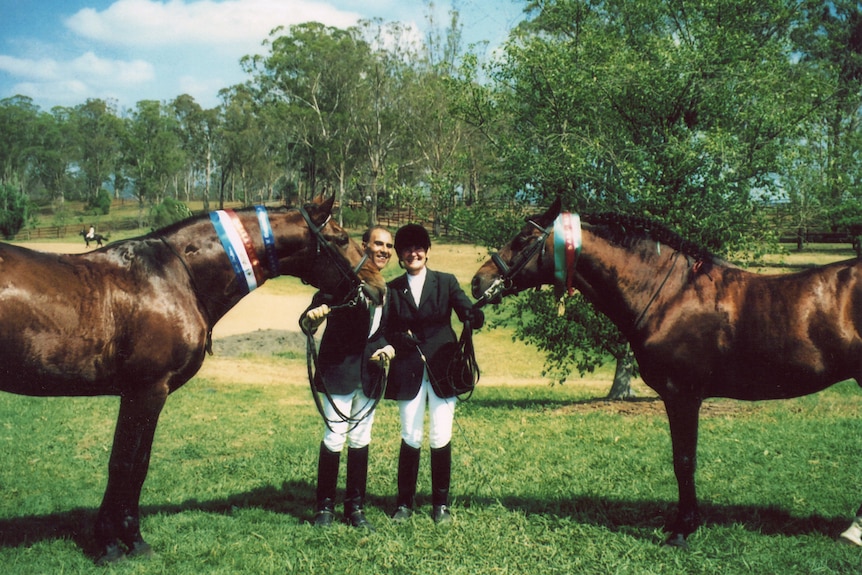 A man and a woman stand next to two show horses