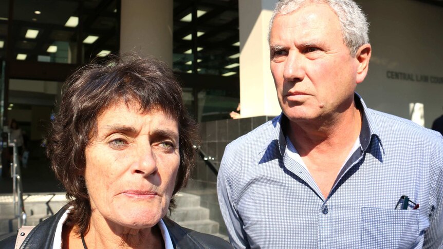 Robyn and Tony Hampton stand outside the Perth Law Courts, with sun shining on their faces.