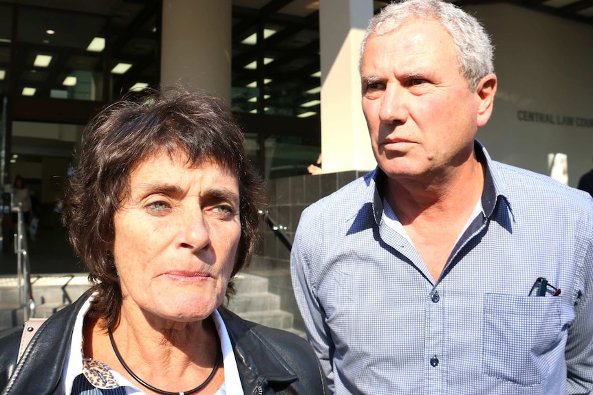 Robyn and Tony Hampton stand outside the Perth Law Courts, with sun shining on their faces.