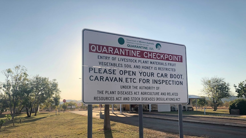A roadside sign warning travellers about quarantine rules