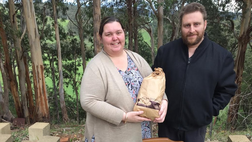 Melissa and Gary Ferguson stand in front of their property holding donations for a farmer relief drive.