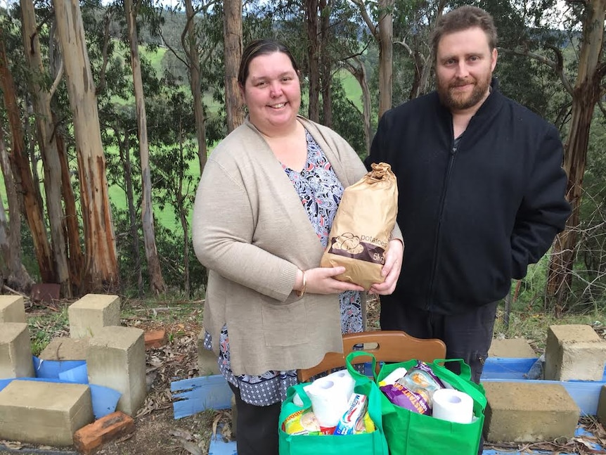 Melissa and Gary Ferguson stand in front of their property holding donations for a farmer relief drive.