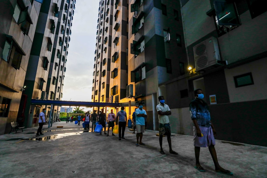 A line of men in between two buildings as the sun sets