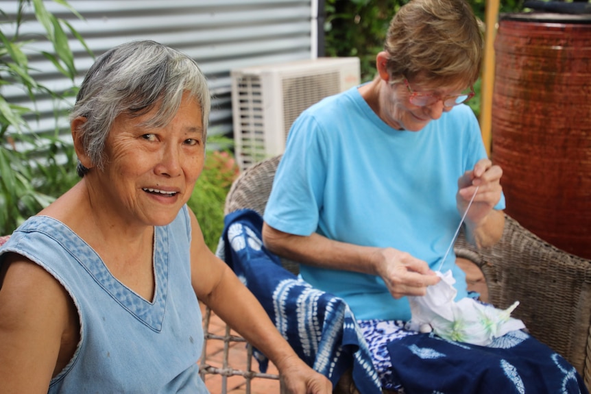 Two ladies sitting down stitching.