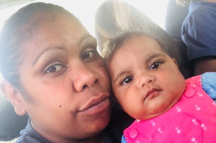 An Aboriginal woman cuddles a baby girl