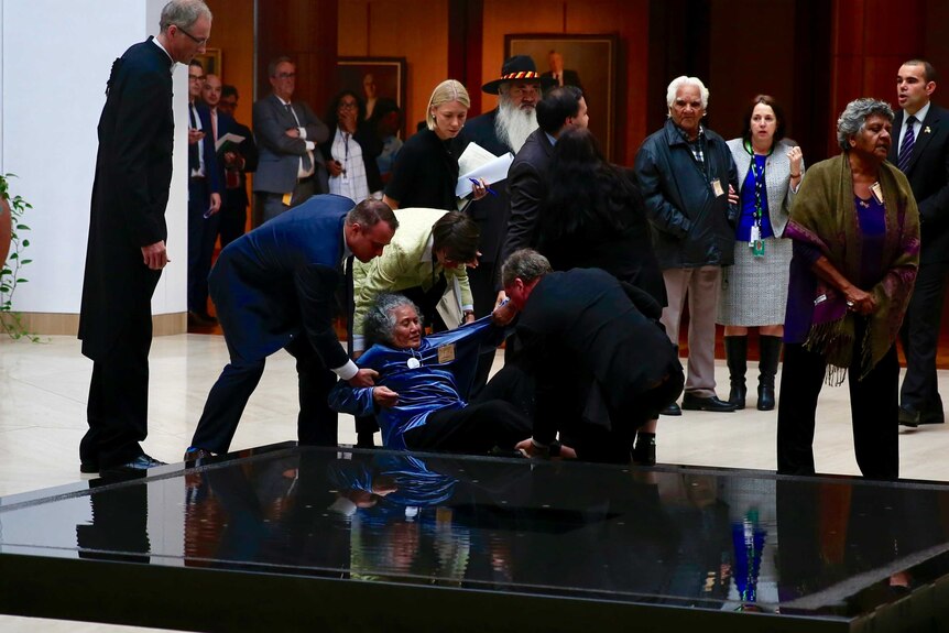Barnaby Joyce and others lift a woman from a water feature in Parliament House in Canberra.