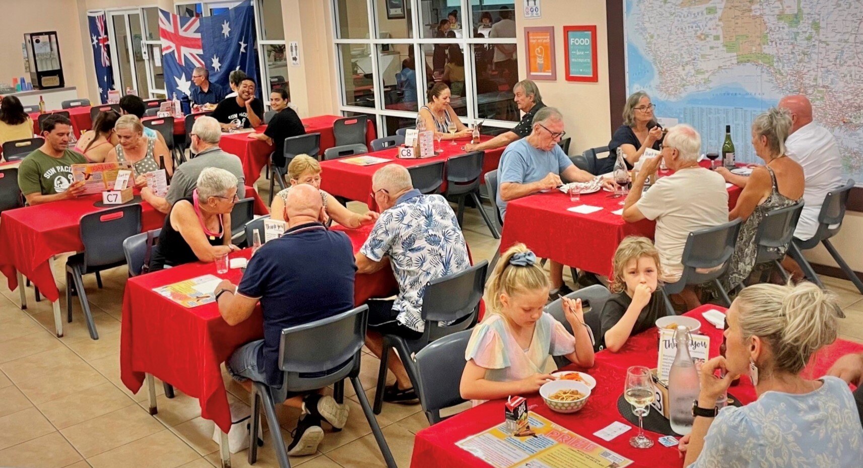 families sitting down at tables inside a restaurant 